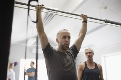 Mid adult man lifting barbell pole in gym