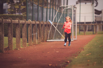 Full length of girl running at soccer field