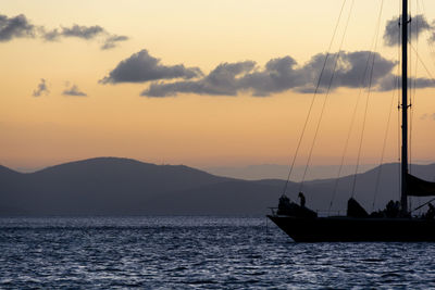 Sailboat sailing in sea at sunset