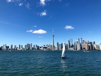 Sailboats in sea against modern buildings in city