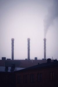 Smoke emitting from factory against sky