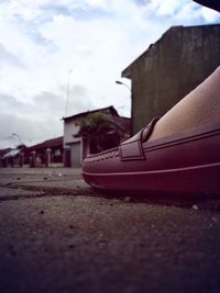 Close-up of shoes on house against cloudy sky