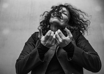 Mature woman gesturing while standing against wall