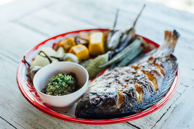 High angle view of fish with vegetables served on wooden table