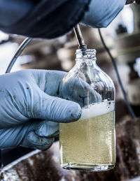 Cropped hands of worker filling bottle in factory