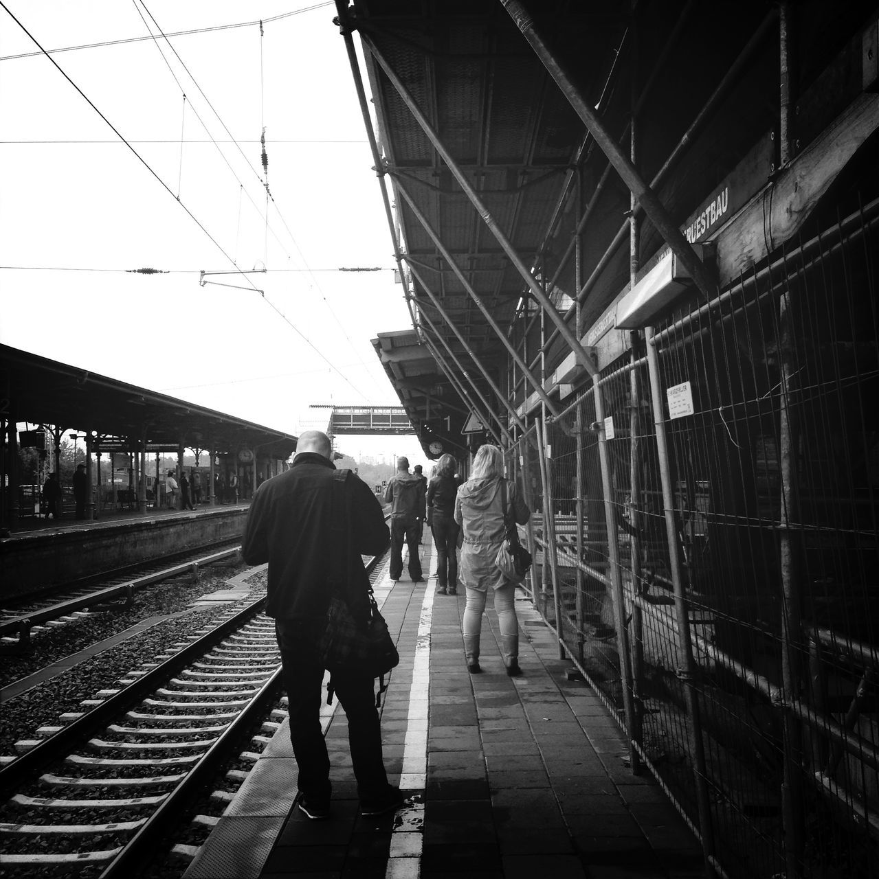 men, walking, rear view, full length, architecture, built structure, lifestyles, person, railroad track, building exterior, the way forward, leisure activity, rail transportation, city, city life, transportation, railroad station platform