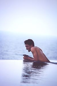 Man in swimming pool against sea