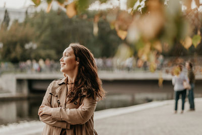 Young woman looking away while standing outdoors