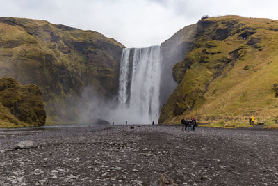 People at skogafoss against sky