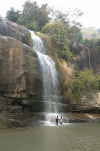 People standing on cliff by river against sky