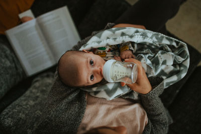 Directly above shot of woman feeding milk to baby boy at home