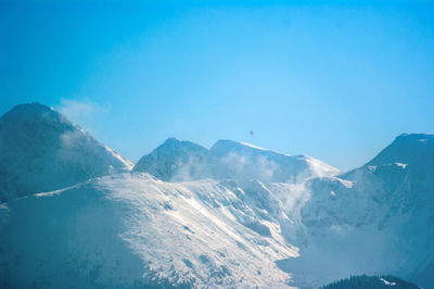 View of hot air balloon flying over snow covered mountain range