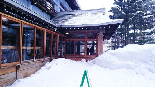 Snow covered house on field by building