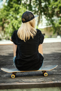 Rear view of woman sitting on skateboard