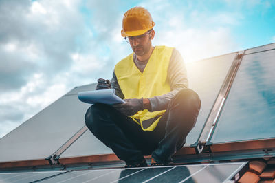 Low angle view of man sitting on slide against sky