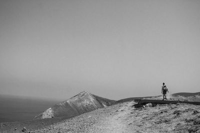 Man standing on shore by sea against clear sky