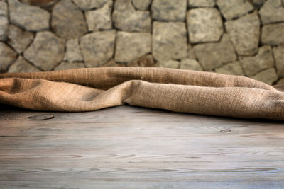 Close-up of rug on floor against stone wall