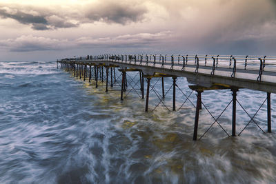 Pier over sea against sky during sunset