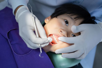 Hand of doctor dentist is working on the teeth of asian little kid patient in dental clinic