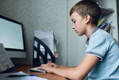 Side view of boy using computer