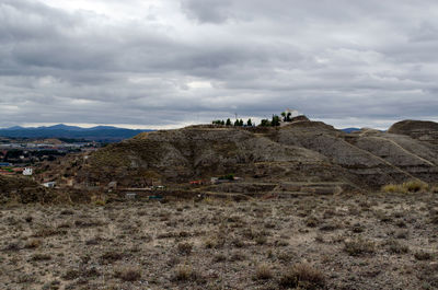 View of tourists on mountain against cloudy sky