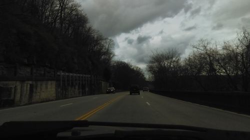 Road passing through landscape against cloudy sky