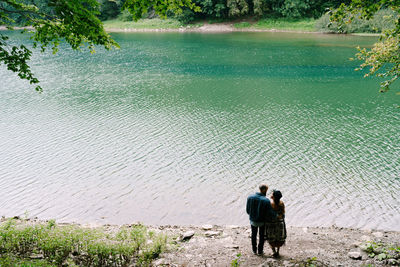 Rear view of people on lake against plants