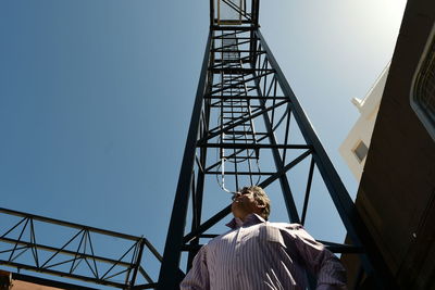 Low angle view of man working against clear sky