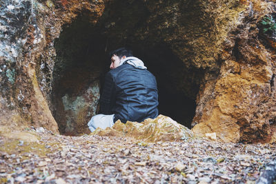 Rear view of man sitting on rock