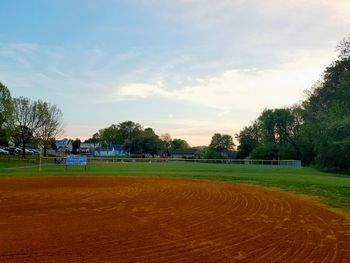 View of field against cloudy sky