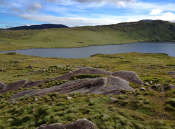 Scenic view of river by hill against sky