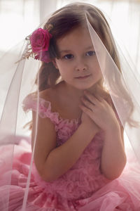 Portrait of a girl in a pink dress and a flower with a rose in her head in the studio