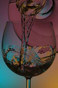 Close-up of wineglass on glass against white background