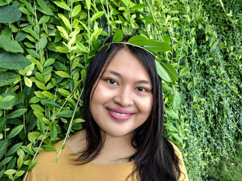 Portrait of smiling young woman against plants 