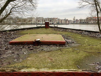 Abandoned building by river against sky in city