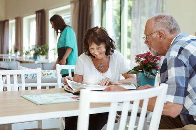 Senior couple reading book together at table in nursing home