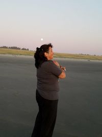 Woman standing on beach against clear sky