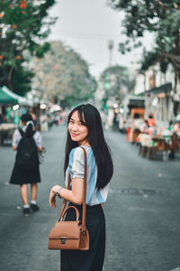 Portrait of woman standing on street in city