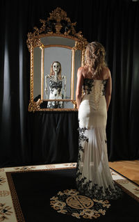 Digital composite image of bride looking at skeleton reflecting in mirror