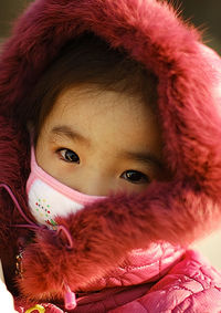 Close-up portrait of cute girl wearing pink hooded jacket