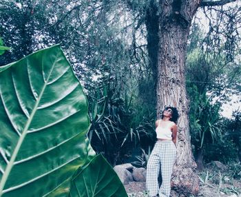 Young woman leaning on tree trunk