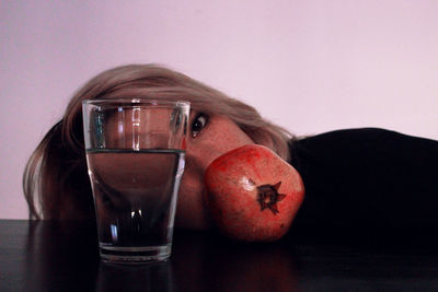 Portrait of woman with pomegranate with drinking glass at table