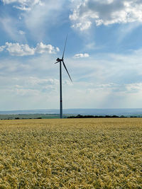 Windmills on field against sky