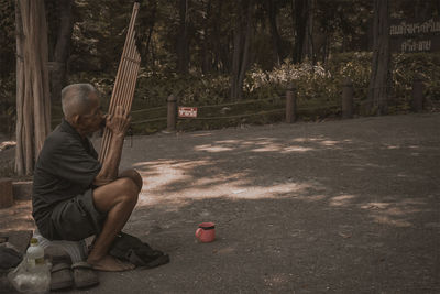 Side view of man sitting in park