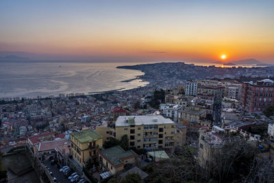 High angle view of townscape by sea against sky during sunset