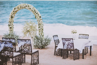 Chairs and table on beach against sea