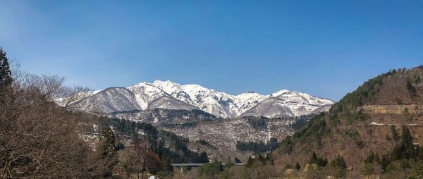Panoramic view of snowcapped mountains against clear blue sky