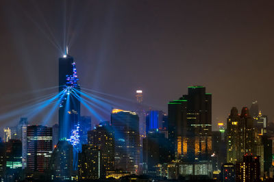 Illuminated buildings in city against sky at night