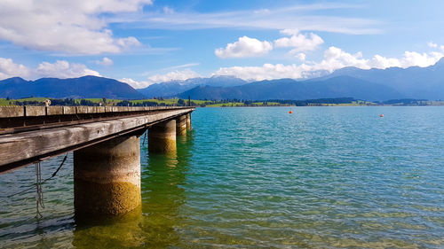 Bridge over sea against cloudy sky