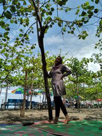 Full length of woman standing by tree at park